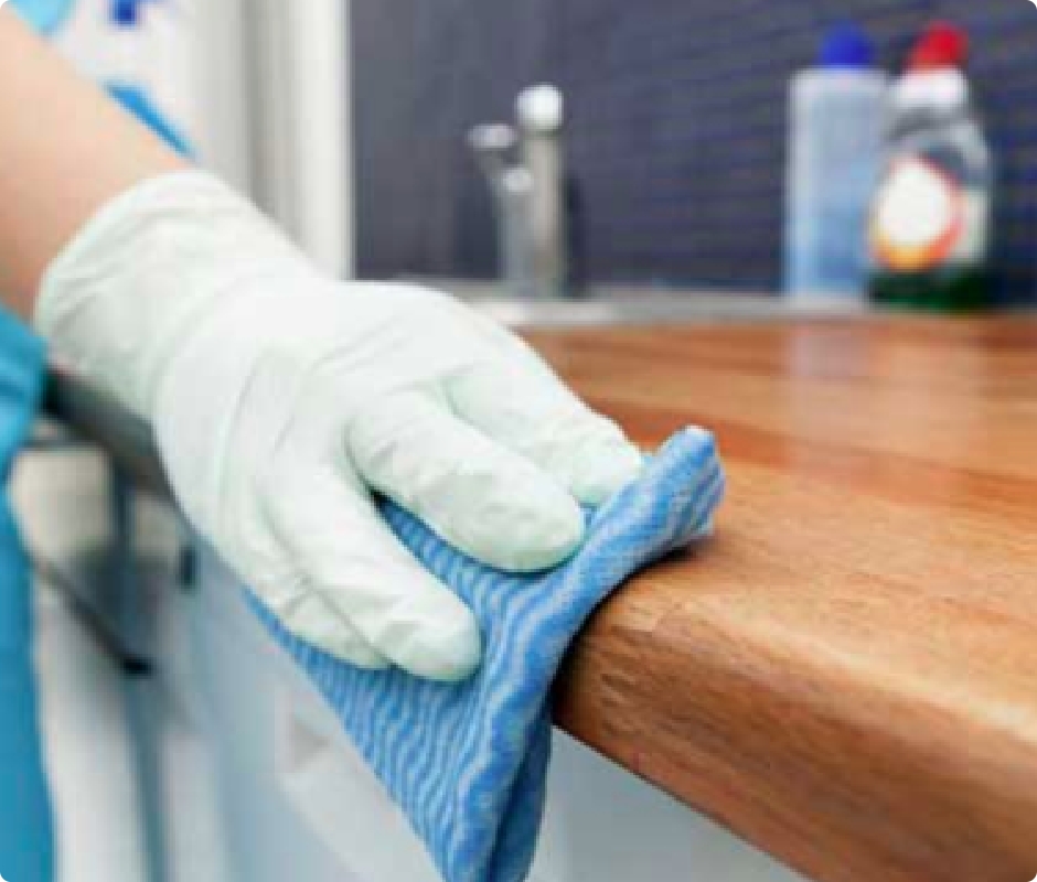 A man cleaning a table with a towel while wearing white gloves