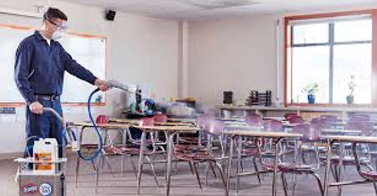 A man using electrostatic spray cleaning technology to clean chairs and tables