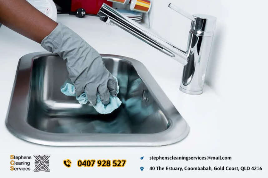 A man cleaning a sink with gray gloves