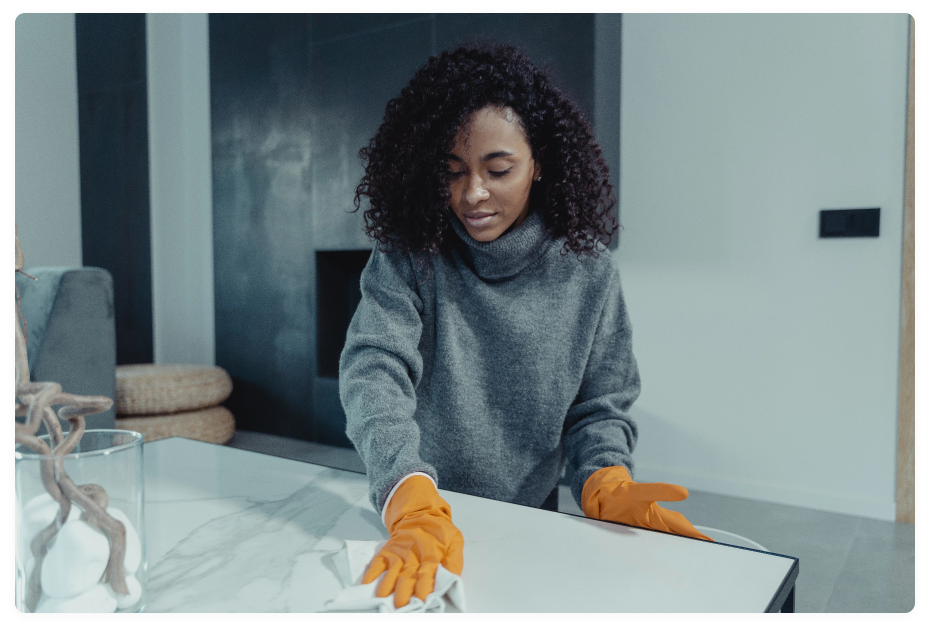 Female cleaning table glass with a towel