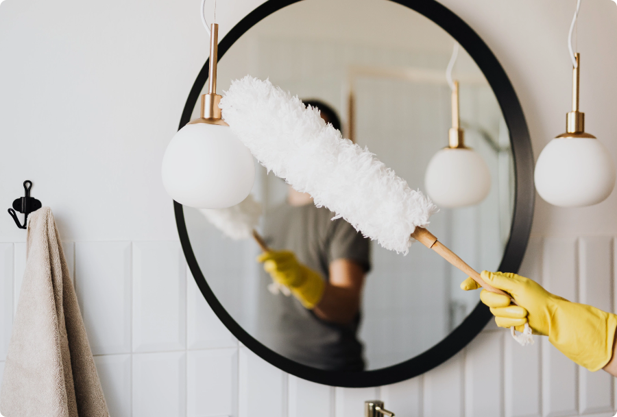 Person hand-mopping a mirror with yellow gloves on