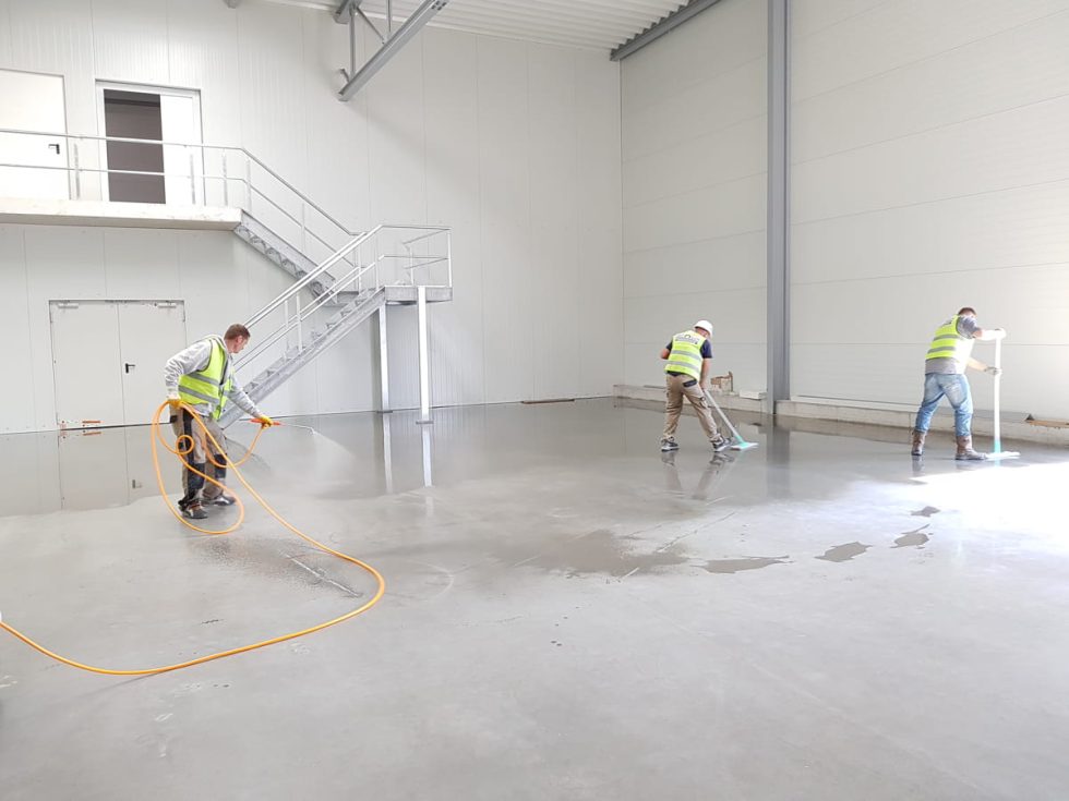 Three men clean the floor with the mopping