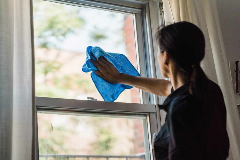 A woman cleaning a window with a towel.