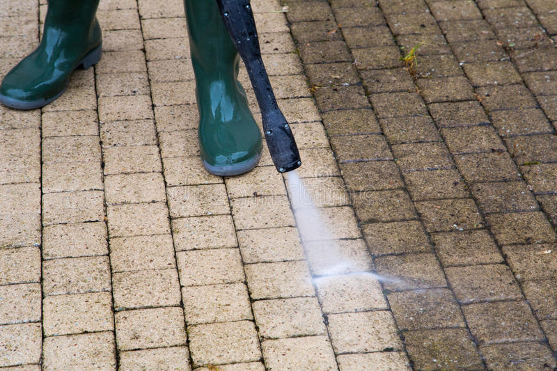 A person using a pressure washer to clean the exterior of a building