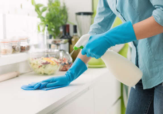 Man cleaning a table with a spray bottle and towel.